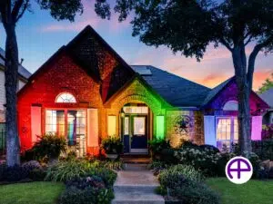 Twilight photo of single-story pride home with landscaping lights creating a large rainbow, featuring accutwilight™ and accusky replacement™ services