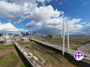 Aerial view of margaret hunt hill bridge with dallas skyline in the background captured by accudrones™, accuaerialphotos™, and accuaerialskyline™.
