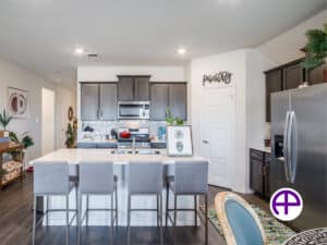 Elegant kitchen showcasing dark cabinets, white quartz countertops, and an island with double sink and seating for four